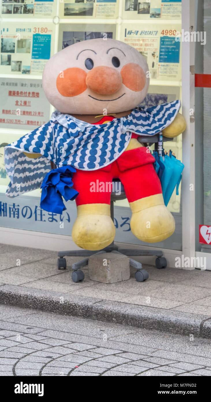 Carino più grande bambola ripiene vestito in pantaloni rossi e blu e bianco sciarpa seduto sulla sedia da ufficio di fronte a Tokyo agenzia immobiliare. Foto Stock
