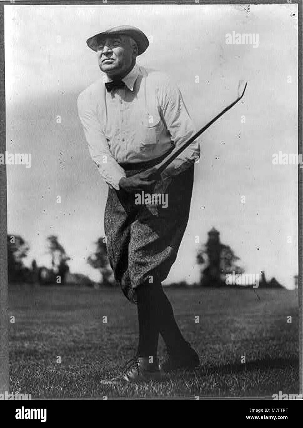 Un ritratto a figura intera di Warren G. Harding, il 29° presidente degli Stati Uniti, raffigurato in una posizione rilassata mentre si muove un golf club. Foto Stock