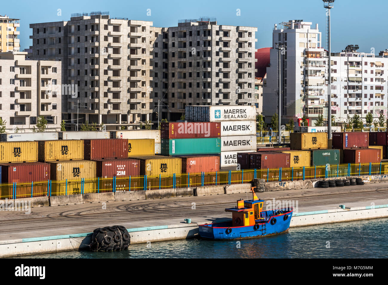 Dures harbour con piccola barca nella parte anteriore del container e il paesaggio urbano, Albania Foto Stock