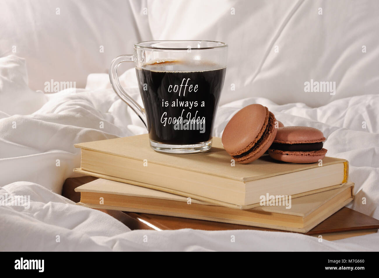 Mattina caffè con torte al cioccolato amaretti, su una pila di libri a letto. Il caffè è sempre una buona idea. Foto Stock