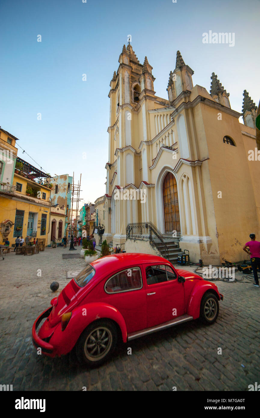 Un rosso classico Volkswagen accanto alla storica chiesa barocca di Havana, Cuba Foto Stock