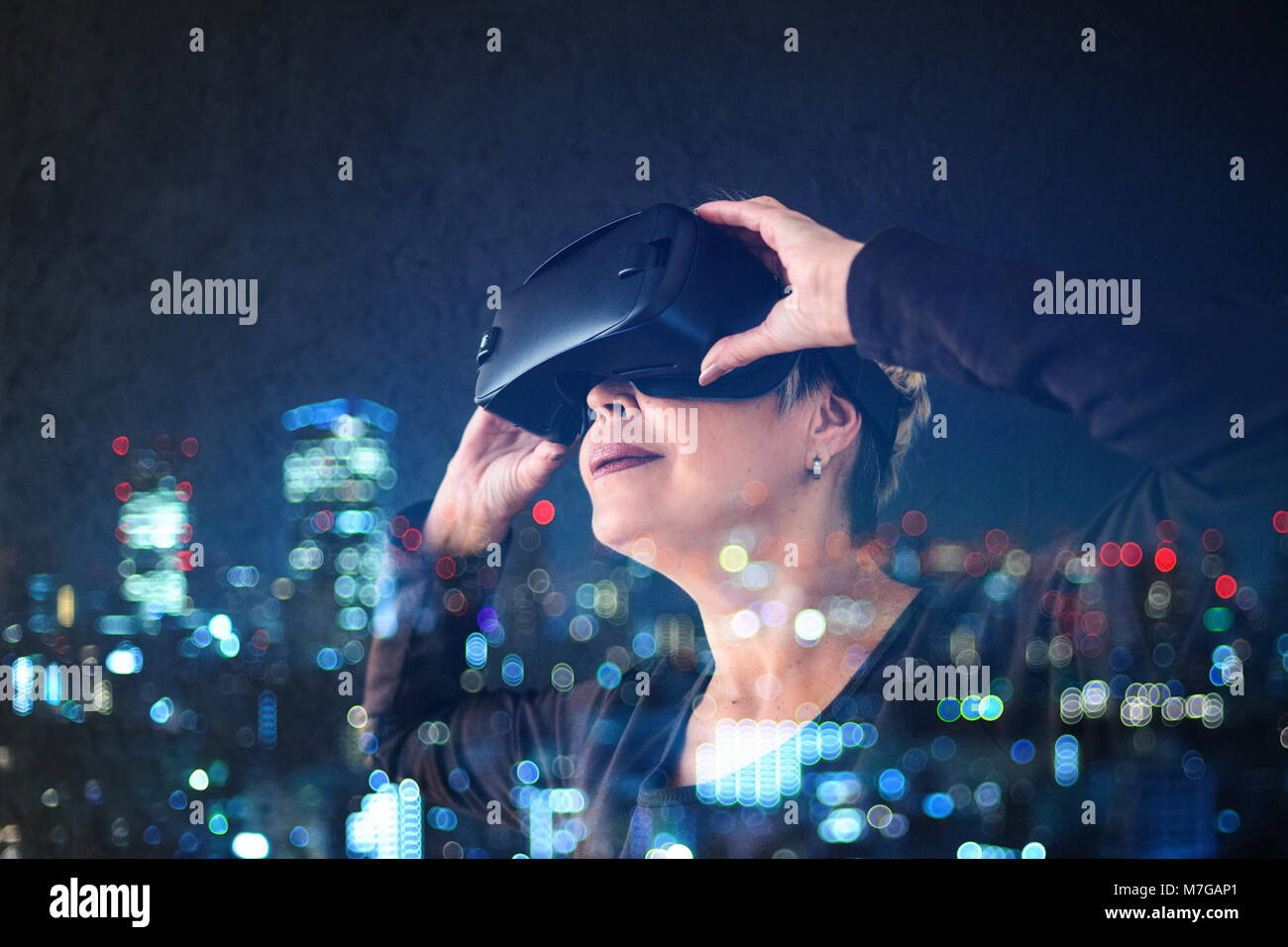 Una donna anziana in realtà virtuale occhiali. Una persona anziana utilizzando la tecnologia moderna. Foto Stock