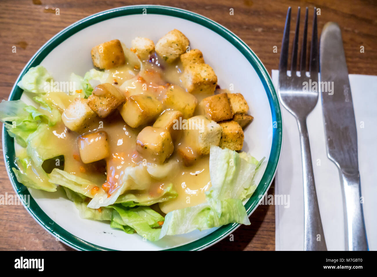Una vista ravvicinata di un piatto di insalata con lattuga e crostini guarnita con un miele la salsa di senape. Foto Stock