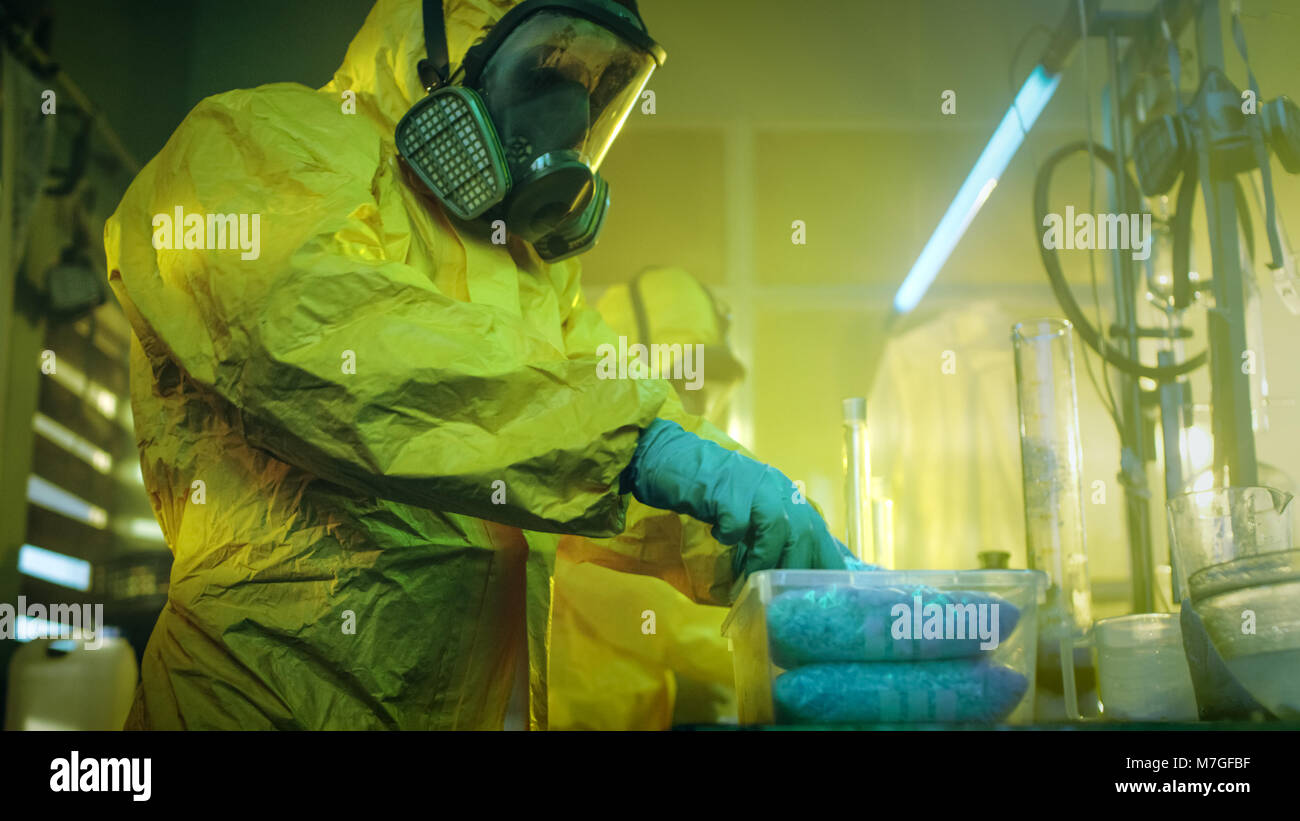 Nel laboratorio sotterraneo clandestino di farmacisti in tute di protezione pacchetto per la distribuzione appena cotte partita di droga. Foto Stock