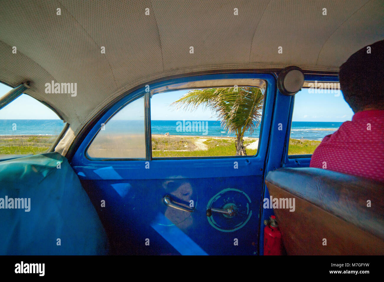 All interno di un classico blu taxi a l'Avana, Cuba, con una vista del mare dei Caraibi fuori dalla finestra Foto Stock