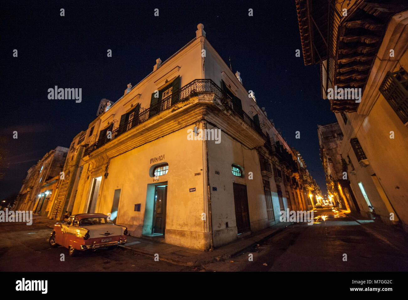 Un classico americano auto parcheggiate fuori una farmacia a l'Avana, Cuba, a notte Foto Stock