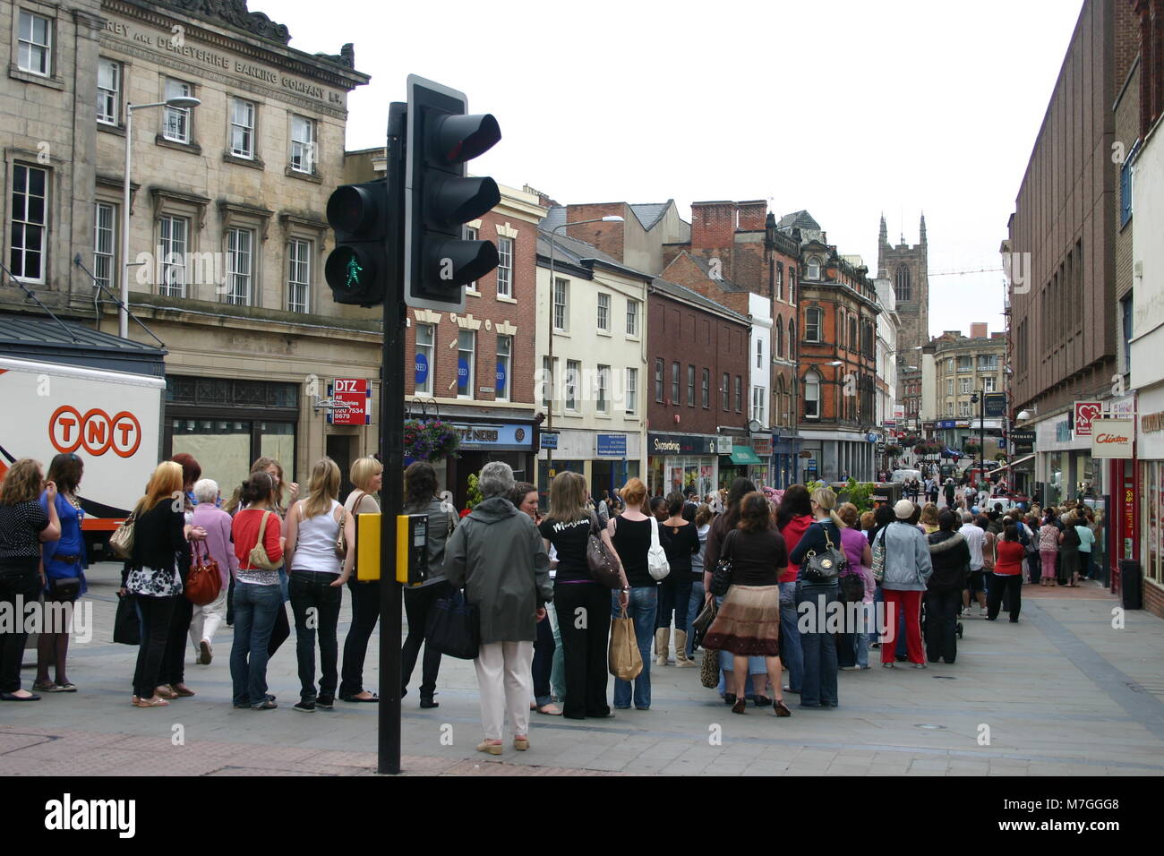 Le vendite con i clienti formando una lunga coda al di fuori di un negozio al dettaglio Derby, Regno Unito Foto Stock