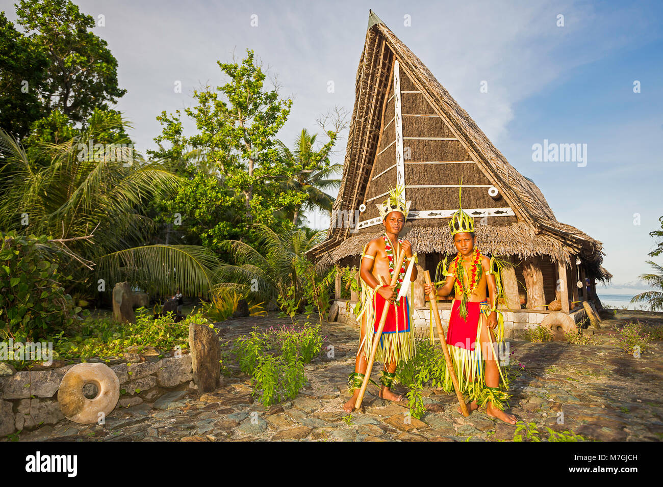 Questi due giovani ragazzi in abiti tradizionali per le cerimonie culturali sono in piedi di fronte ad un uomo di casa sulla isola di Yap, Micronesia. Foto Stock