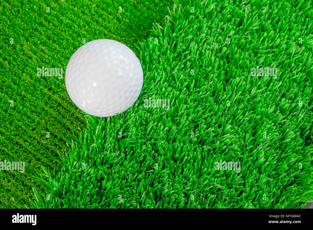 White pallina da golf sul green di erba artificiale. Pratica messa sul bordo tra il ruvido e verde Foto Stock