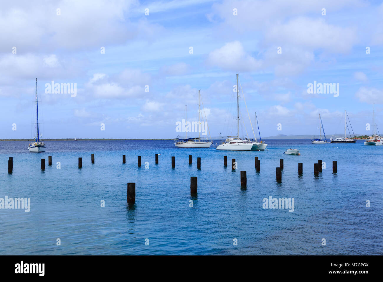 Barche a vela bianca al di là di palificazioni di legno in Bonaire Foto Stock