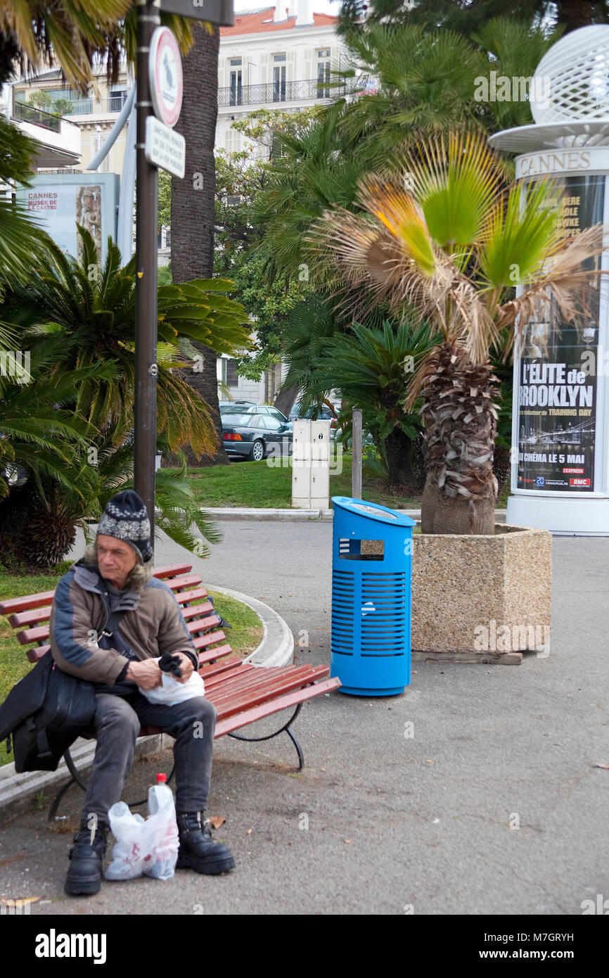 Poveri senzatetto persona seduta su una panchina di Boulevard La Croisette, Cannes, Costa Azzurra, Francia del Sud, Francia, Europa Foto Stock