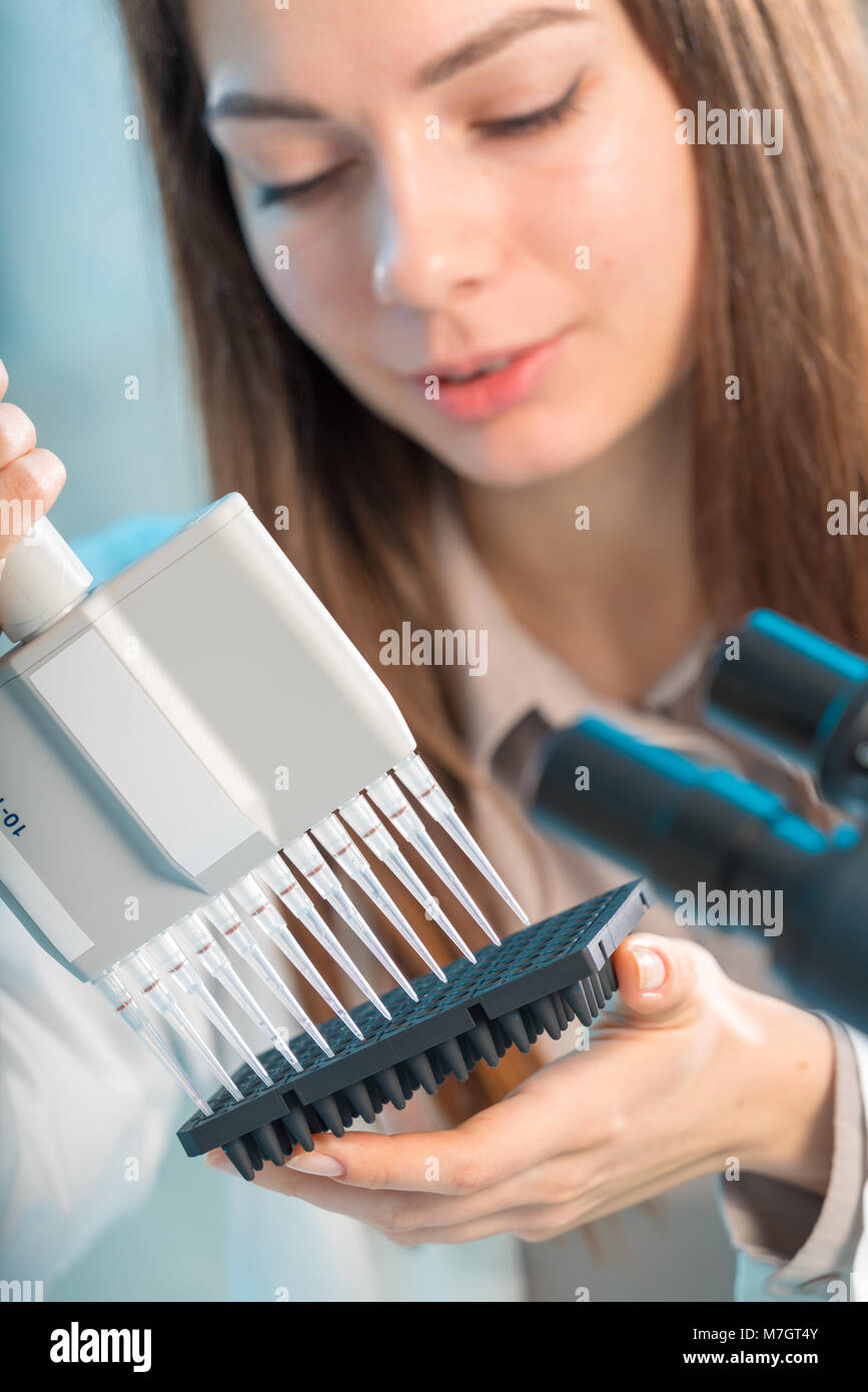 Studente donna con pipetta multipla e di altri elementi di PCR in / microbiologico laboratorio di genetica Foto Stock