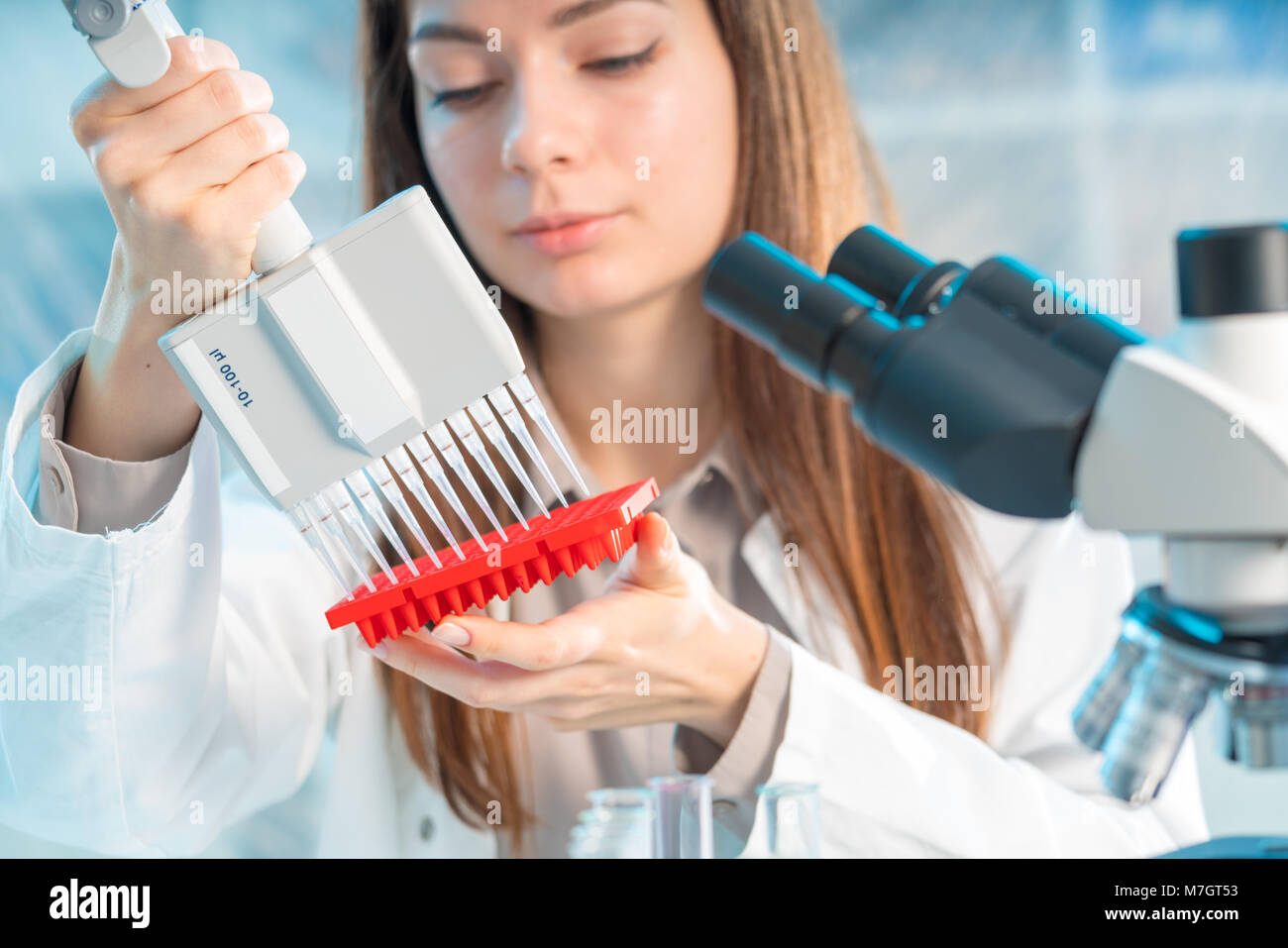 Studente donna con pipetta multipla e di altri elementi di PCR in / microbiologico laboratorio di genetica Foto Stock