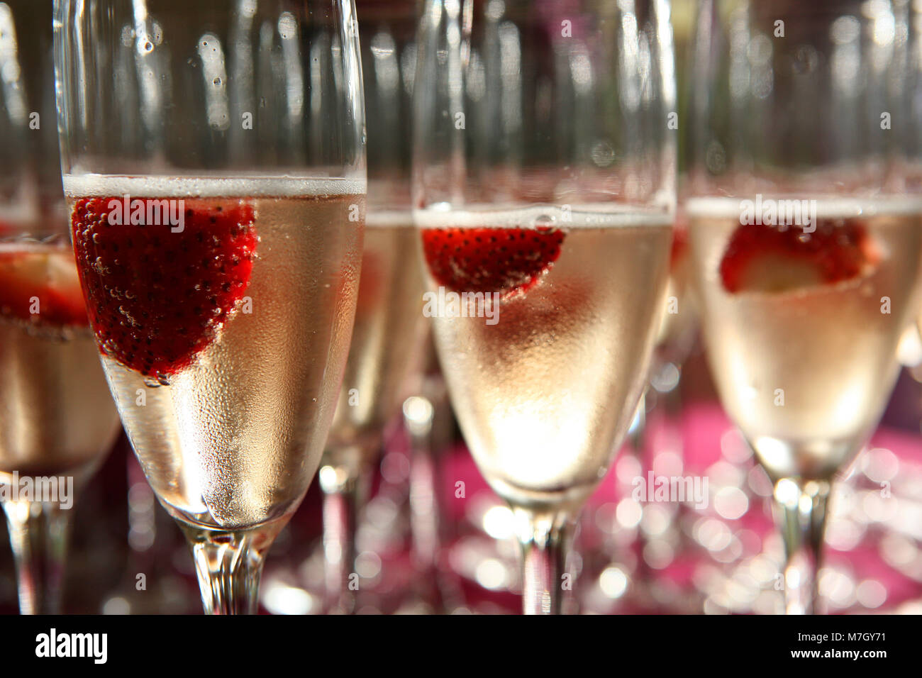 Vetro di champagne con fragole all'interno vicino a molti altri vetri Foto Stock