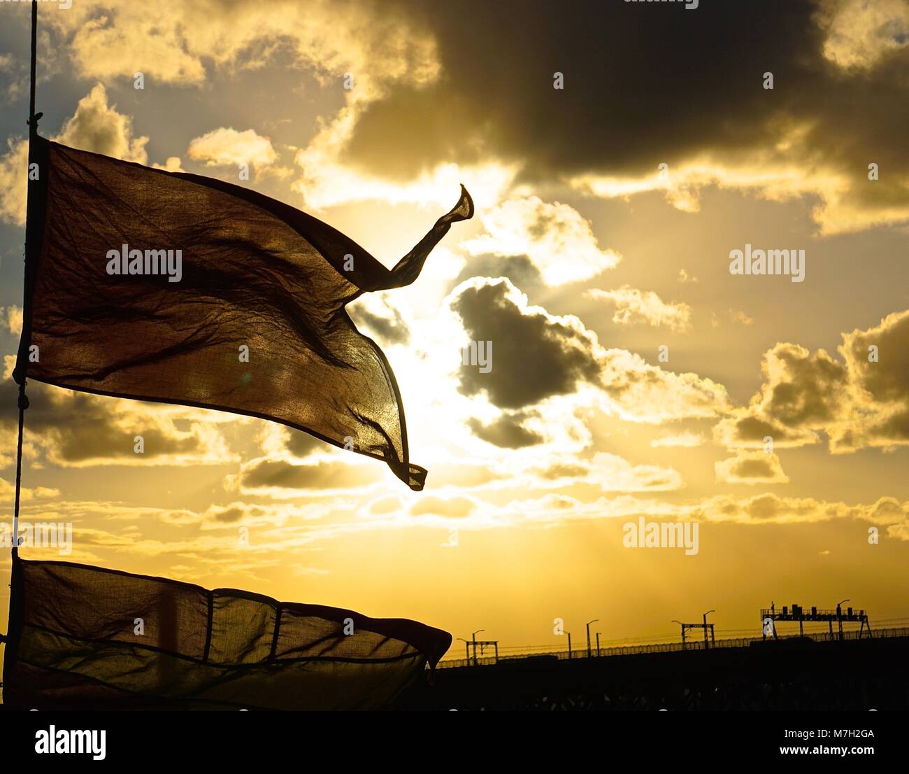 Bandiera sventolare nel vento con il tramonto in background. Foto Stock