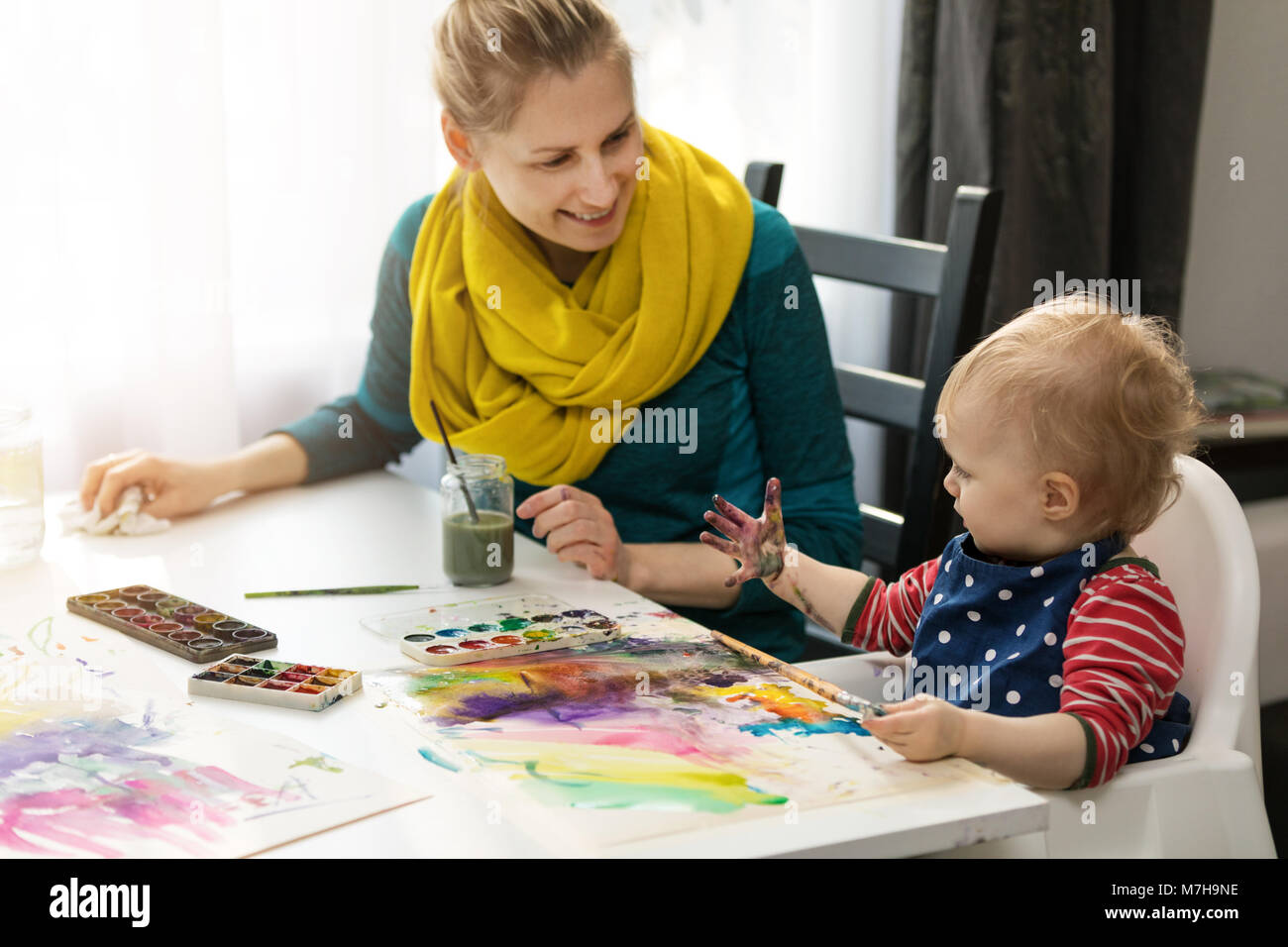 Madre e figlia facendo la pittura ad acquerello - ragazza guardando la sua mano sporca Foto Stock