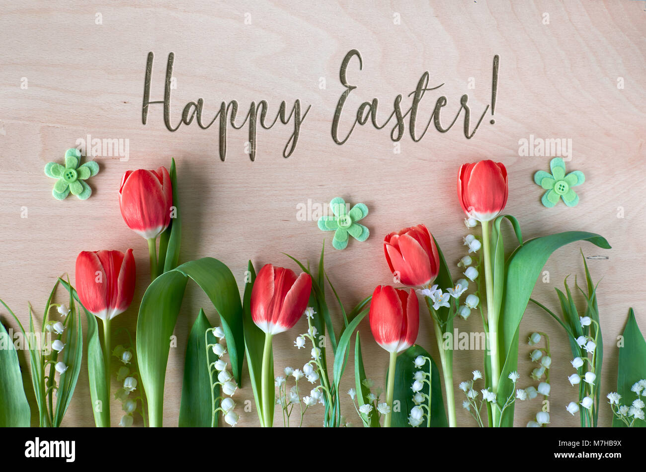 Composizione di pasqua con fiori di primavera, tulipani e il giglio della valle su legno. Testo 'Felice Pasqua' in rilievo su legno Foto Stock