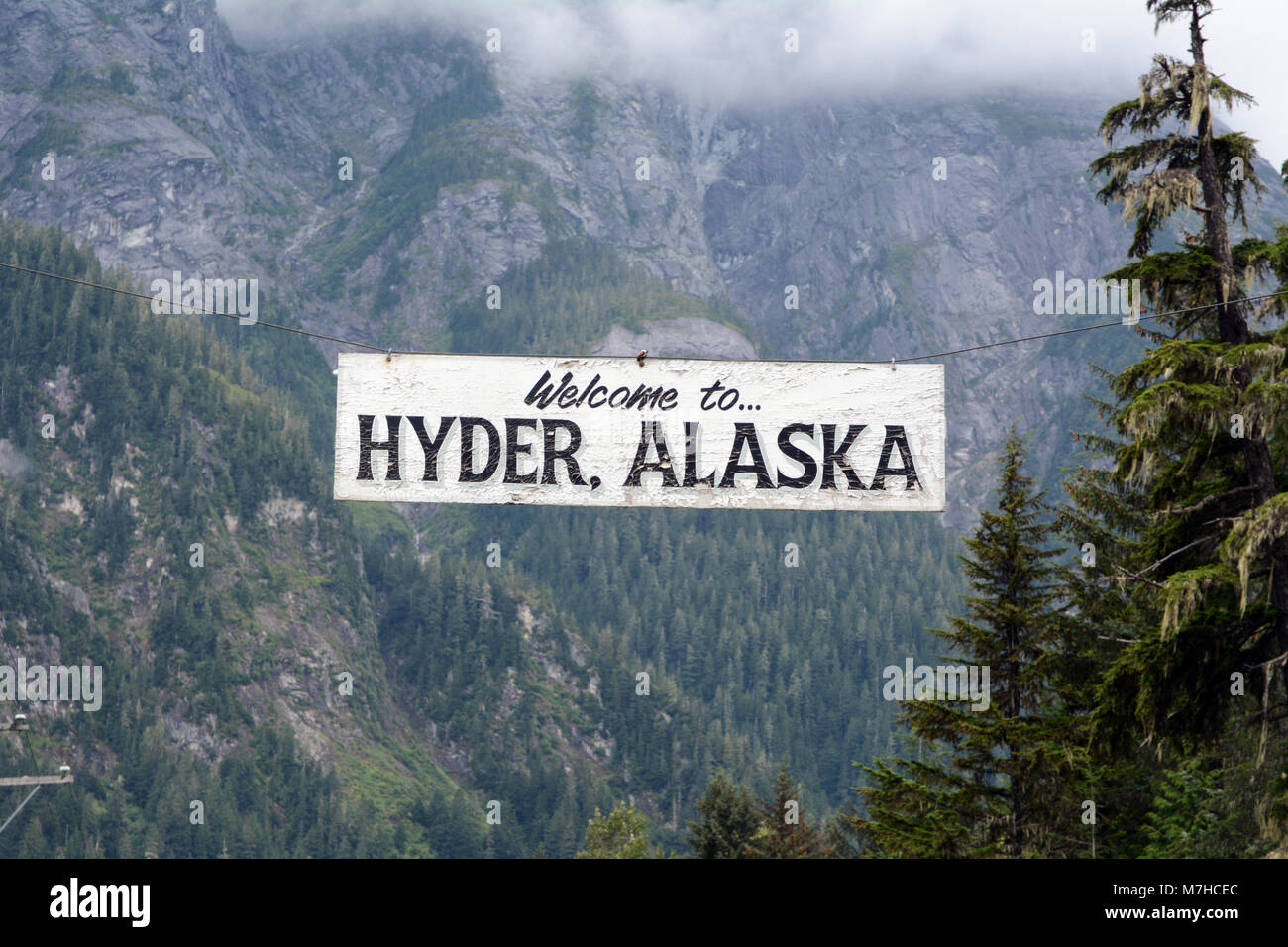 Un segno di benvenuto è appeso sopra la strada di ingresso alla vecchia città mineraria di Hyder, Alaska, Stati Uniti d'America, al di là del confine con Stewart, British Columbia, Canada. Foto Stock