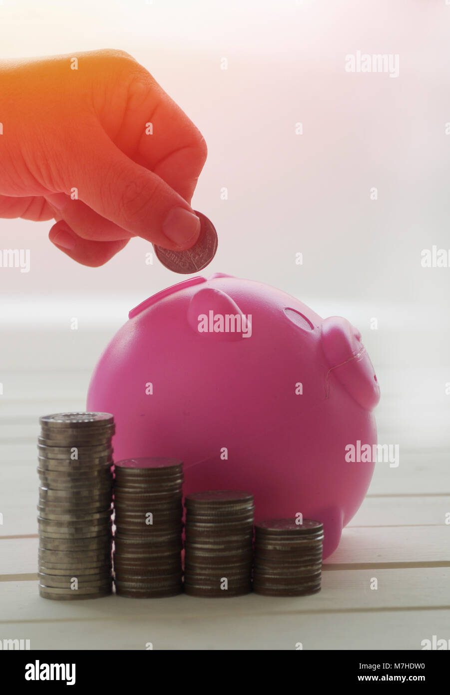 Monete in euro impilate su un tavolo con salvadanaio rosa per risparmiare  denaro. ideale per layout di siti web e riviste
