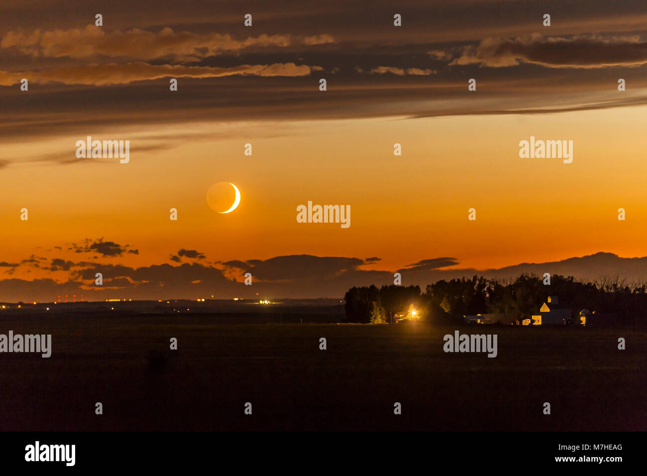 La luna crescente impostazione su una vicina fattoria in Alberta, Canada. Foto Stock