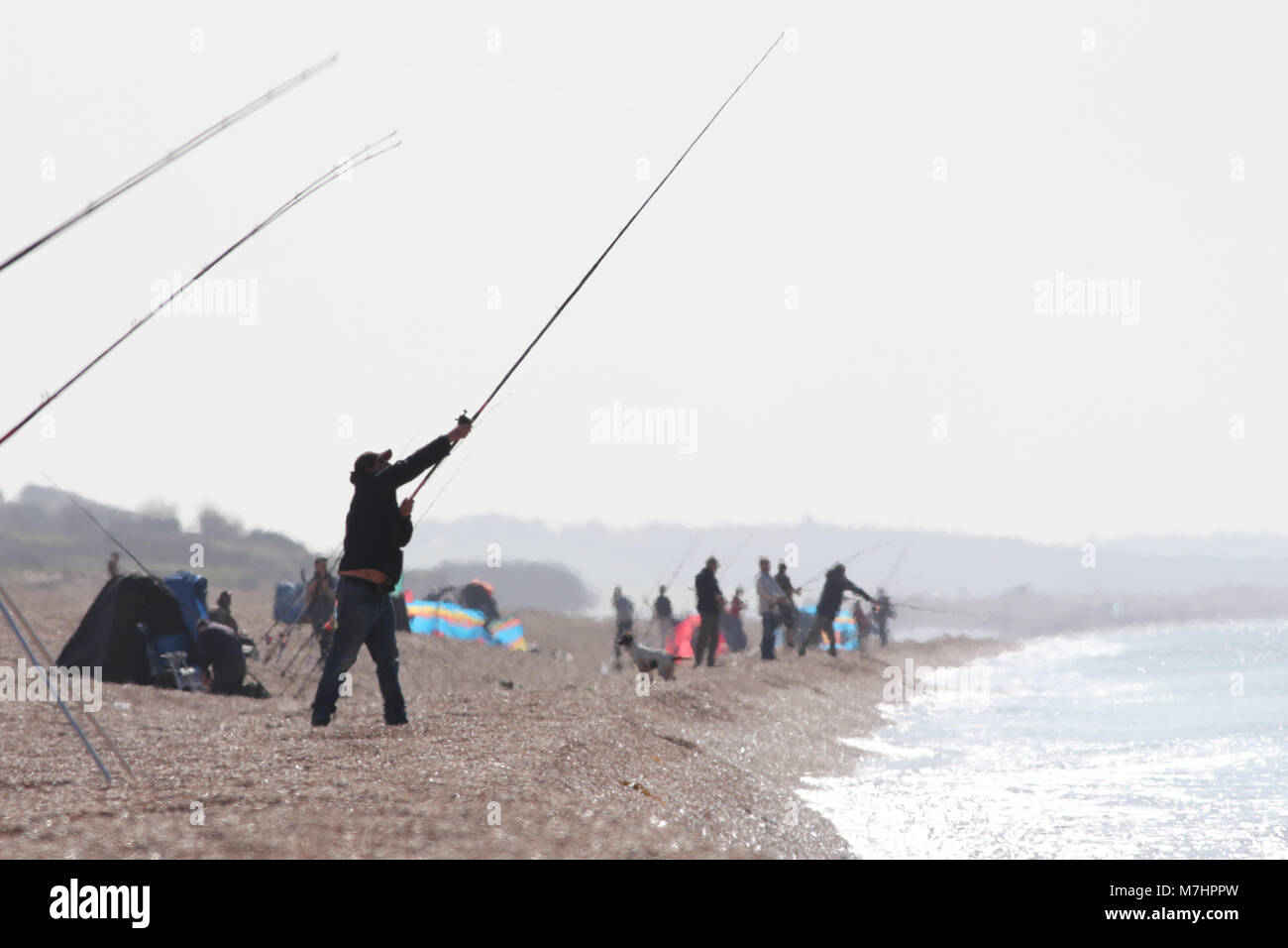 I pescatori in un Haze di calore su un bruciante giorno su Chesil Beach UK, principalmente per la pesca dello sgombro Foto Stock