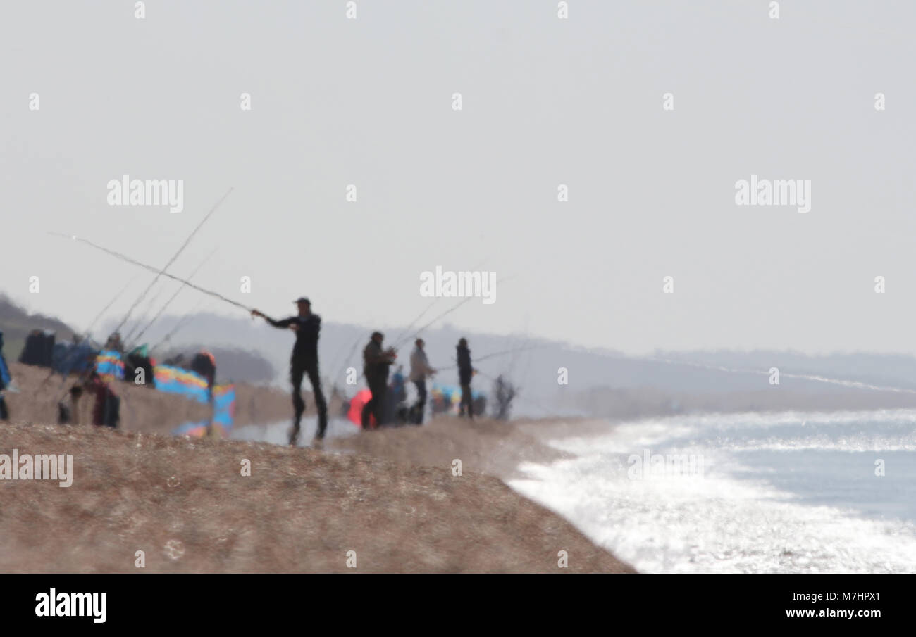 I pescatori in un Haze di calore su un bruciante giorno su Chesil Beach UK, principalmente per la pesca dello sgombro Foto Stock