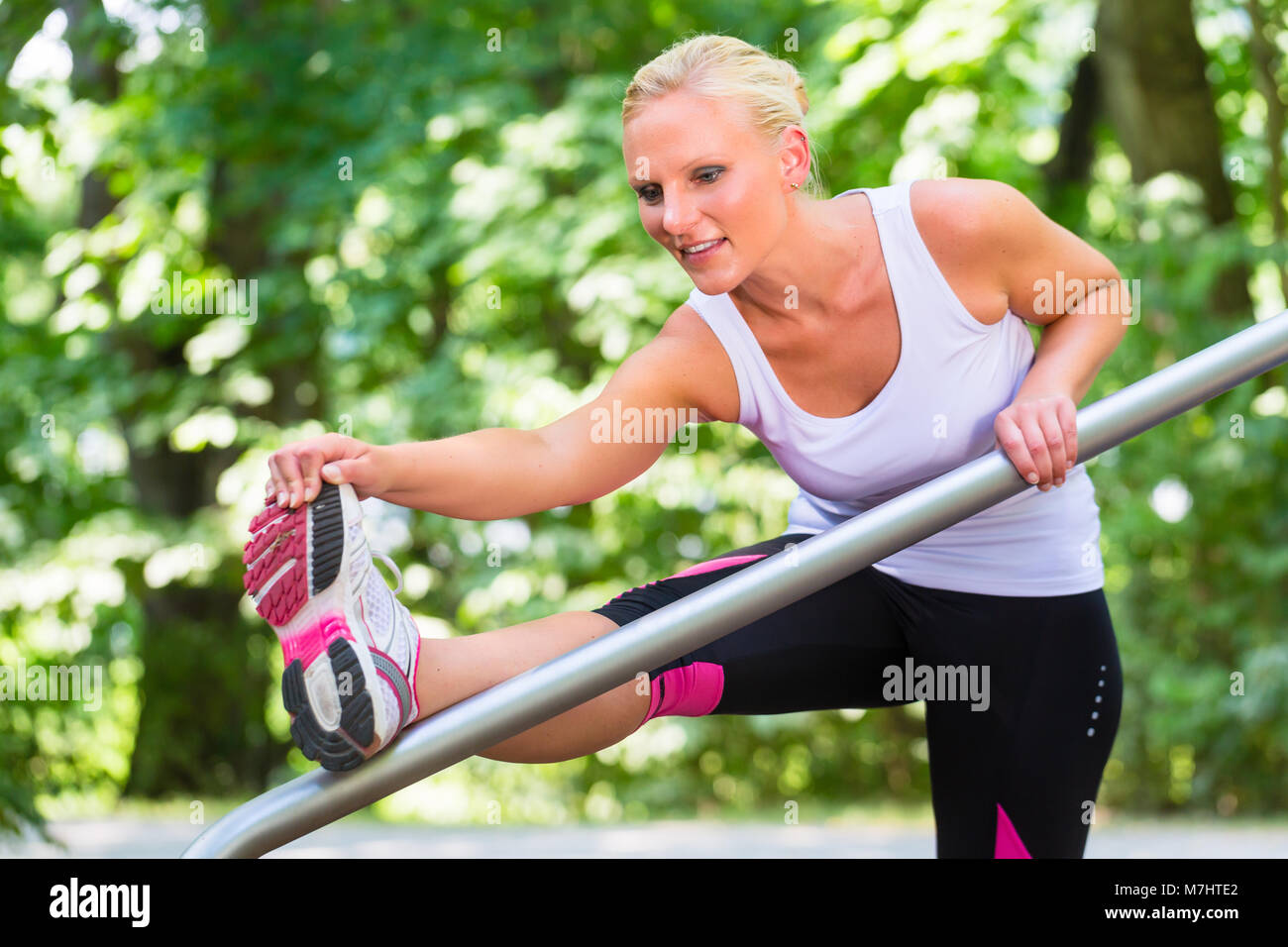 Giovane donna stretching prima di sport sul percorso fitness all'aperto Foto Stock