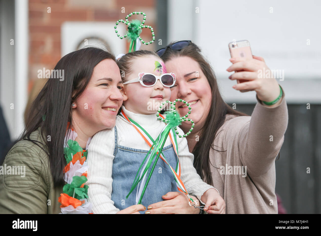 Birmingham's Irish comunità celebra il giorno di San Patrizio con la loro annuale sfilano per le vie della città. La città's Parade è il terzo più grande in tutto il mondo, dietro solo a New York e Dublino. Un bambino è vestito decorato con trifogli pur avendo un selfie prese. Foto Stock