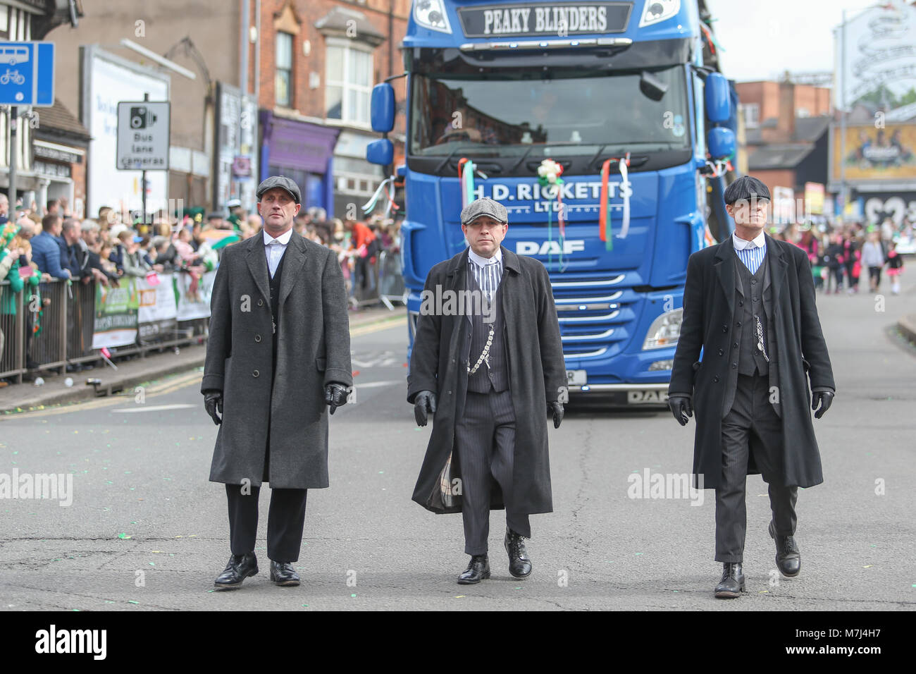 Birmingham's Irish comunità celebra il giorno di San Patrizio con la loro annuale sfilano per le vie della città. La città's Parade è il terzo più grande in tutto il mondo, dietro solo a New York e Dublino. L acclamato programma TV Peaky Blinders fa la sua comparsa. Foto Stock