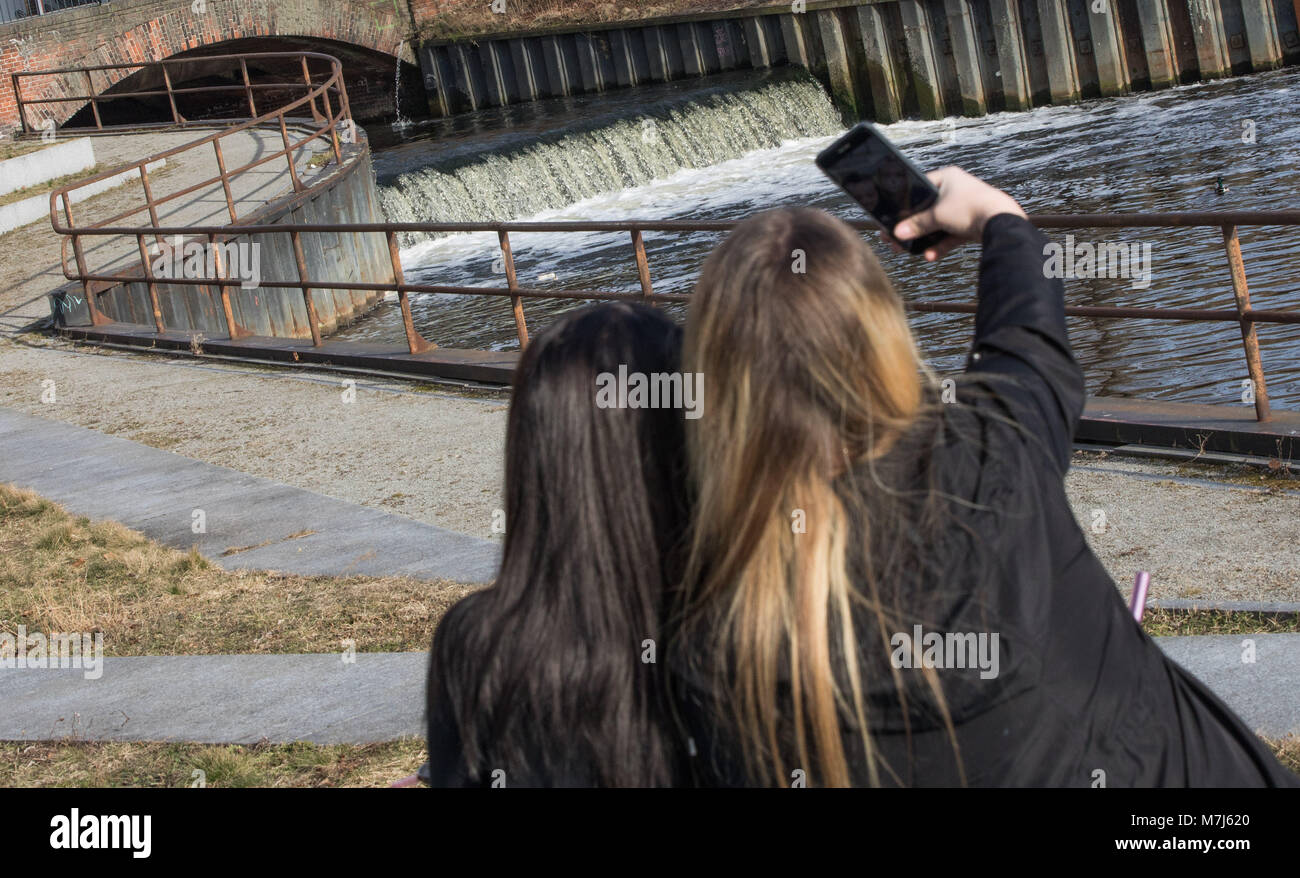 11 marzo 2018, Germania Berlino: due giovani donne prendere un selfie con il fiume Panke in esecuzione nella Nordhafen in background. Foto: Jörg Carstensen/dpa Foto Stock