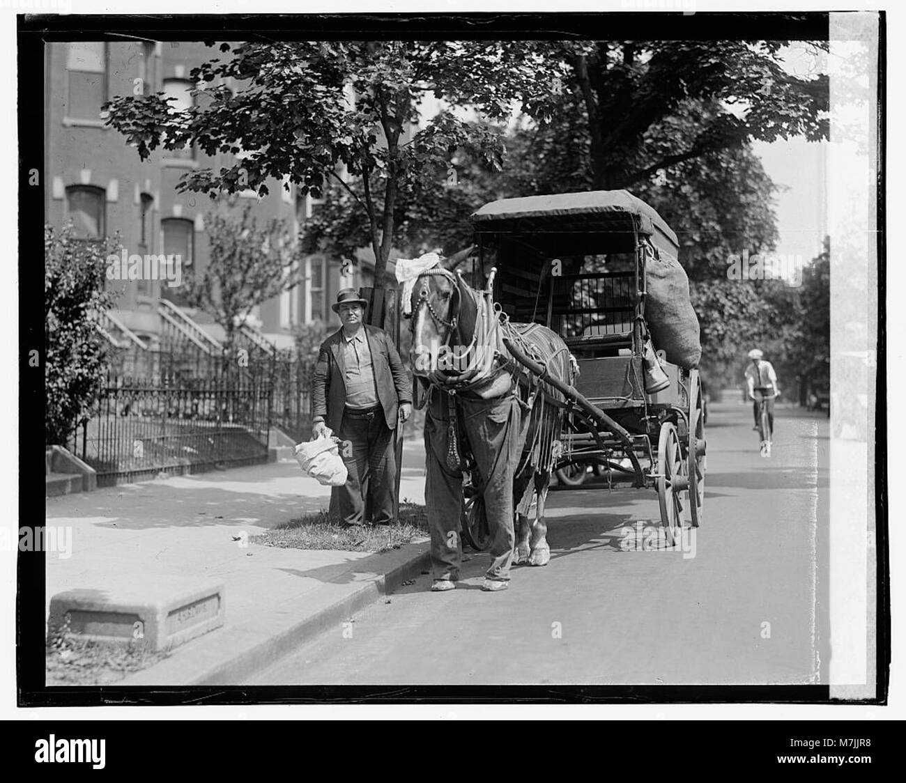 Questa fotografia mostra un cavallo che tira un carro lungo una strada, offrendo uno sguardo sui metodi di trasporto in uso in quel momento, probabilmente riflettendo un ambiente storico o rurale. Foto Stock