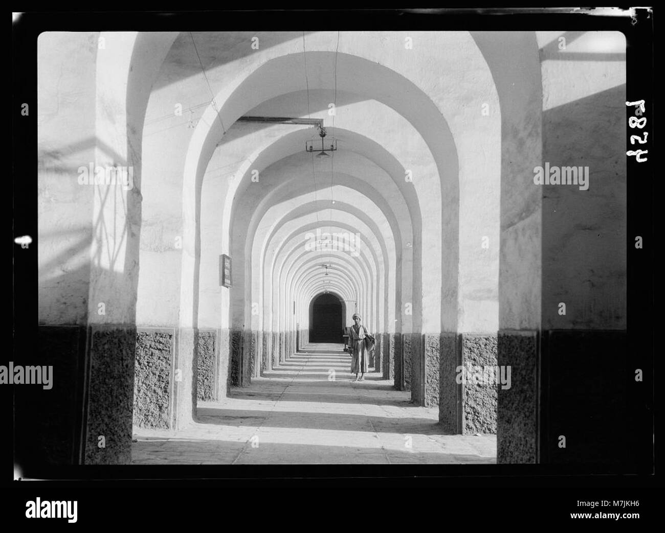 Questa fotografia mostra una scena di strada a Baghdad, Iraq, con una galleria nella vecchia cittadella. L'immagine cattura l'architettura storica della città, con particolare attenzione alla serie di archi che sono una caratteristica significativa della struttura antica. Foto Stock