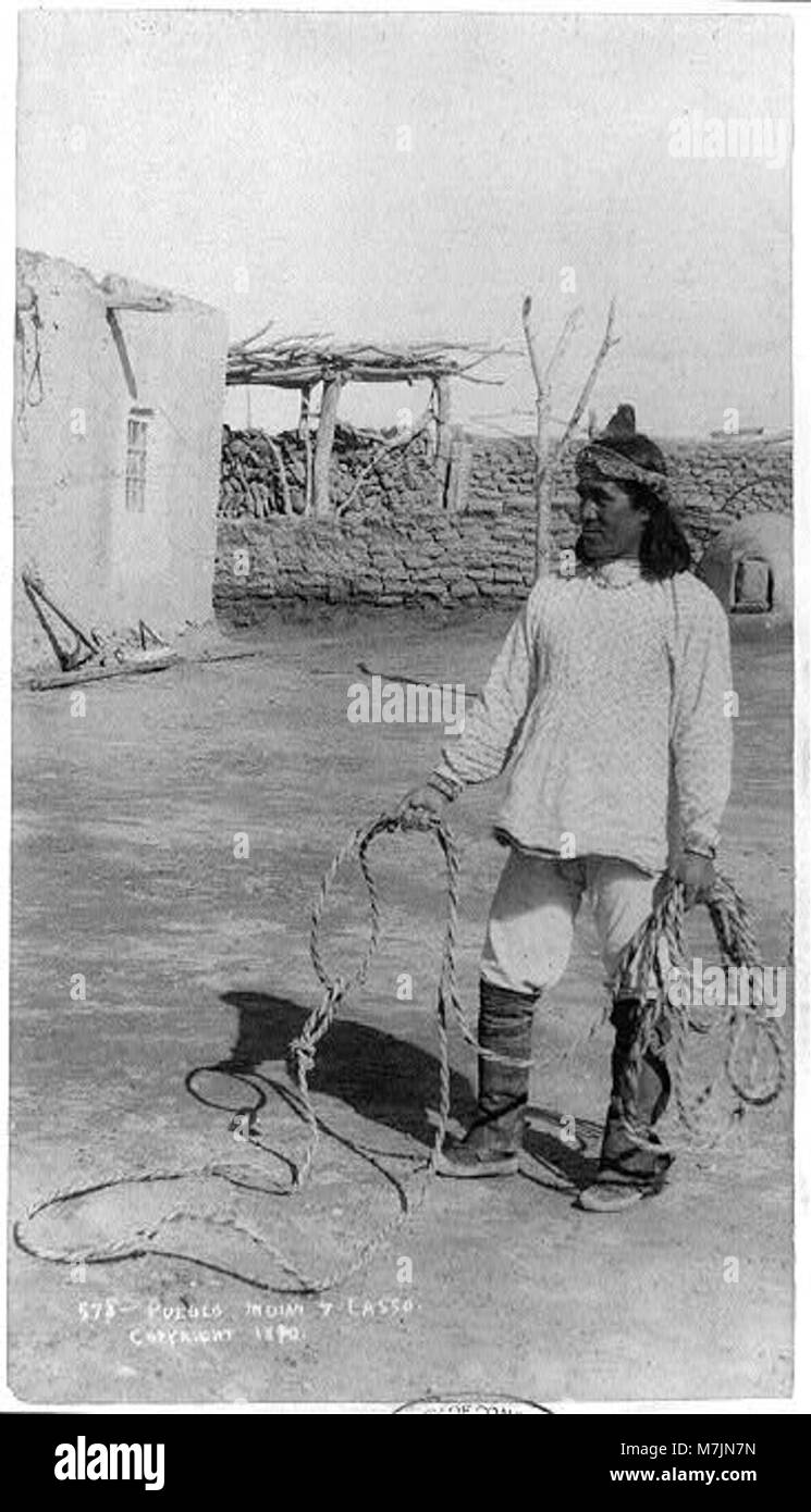 Un'immagine a figura intera di un pueblo indiano che regge un lazo, che mostra un abbigliamento tradizionale e un legame con le pratiche culturali del sud-ovest americano. Foto Stock