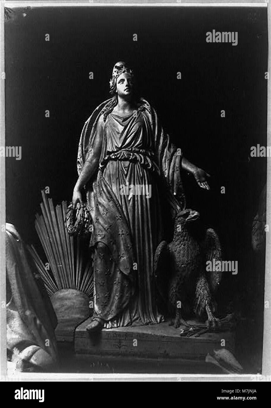 Questa scultura raffigura una figura femminile drappeggiata in una veste con un'aquila accanto a lei, che stringe frecce. L'opera è firmata dall'artista J. Crawford e presenta elementi simbolici classici che rappresentano la forza e la libertà. Foto Stock