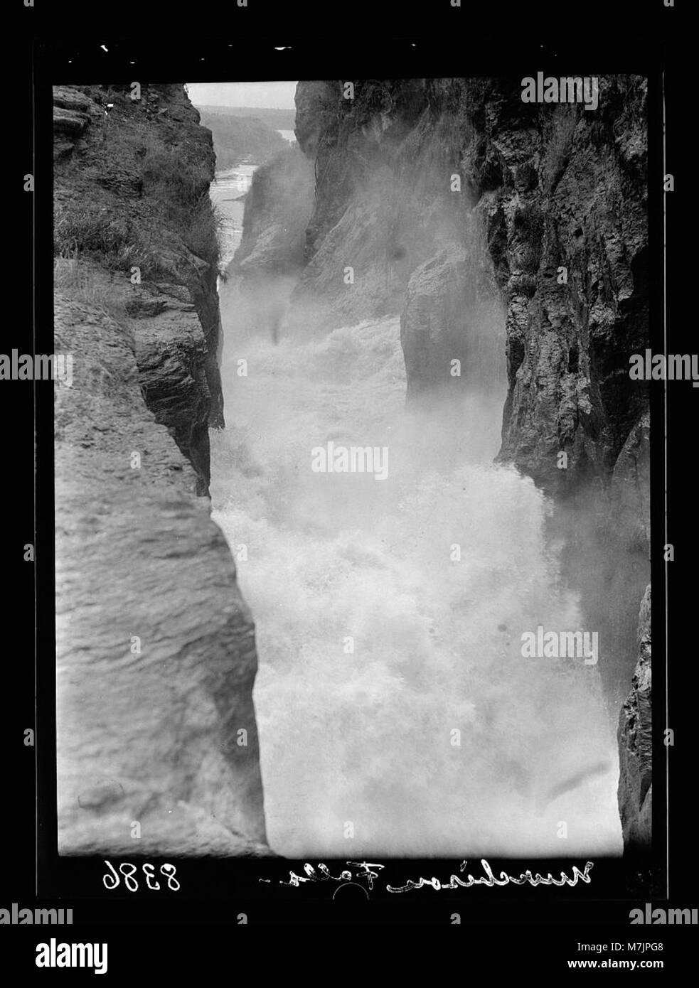 Una vista spettacolare del Nilo Victoria, catturata da una stretta fessura di roccia, che mostra l'intensa corsa e la schiuma d'acqua mentre cade sopra le cascate, sottolineando il potere della natura. Foto Stock