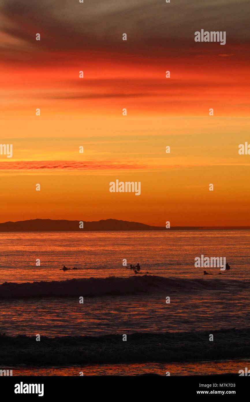 Arancione tramonto con sagome di surfers Foto Stock