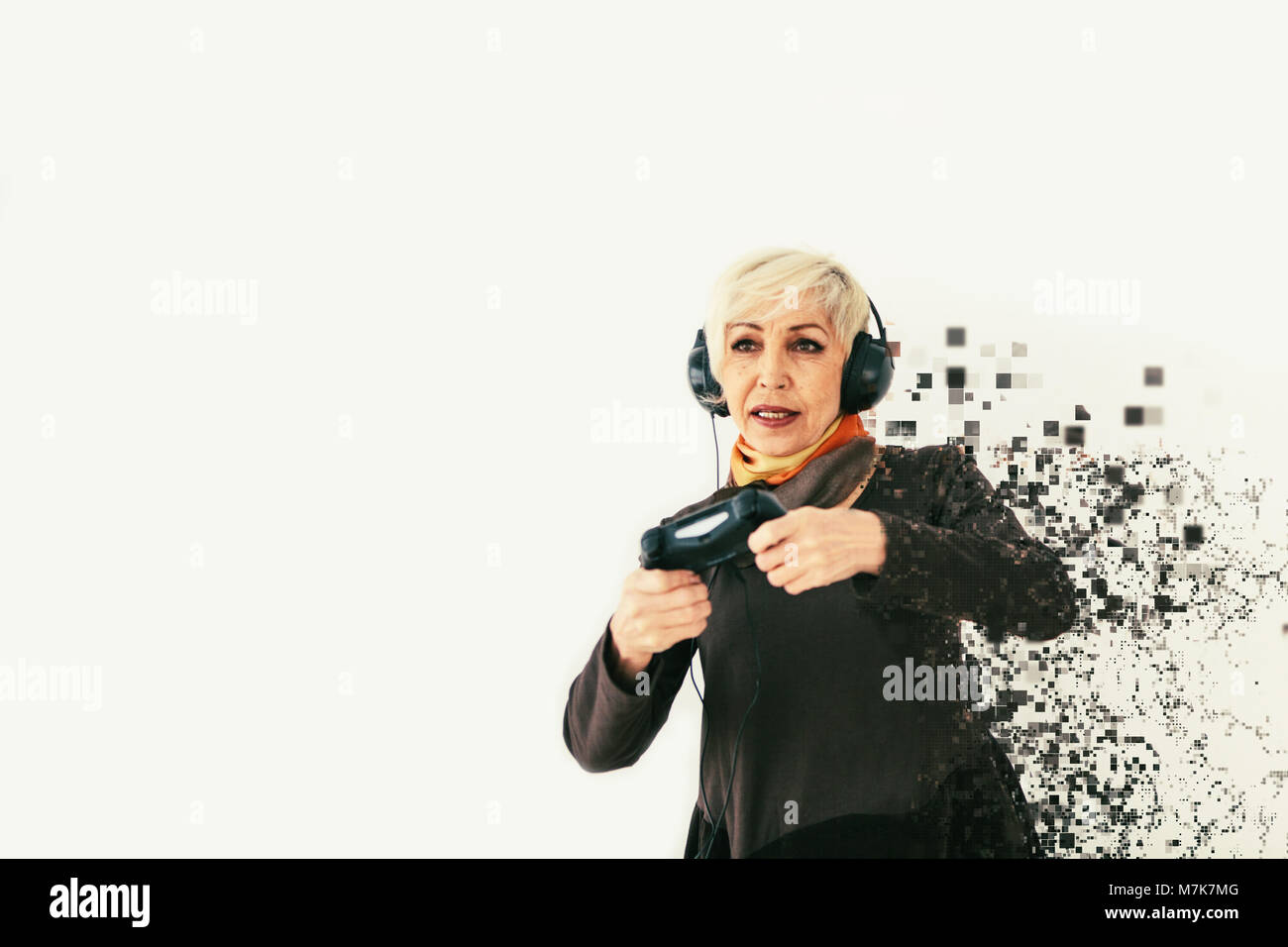 Una donna anziana riproduce un video gioco e viene frammentato in pixel. Una foto concettuale con effetti visivi nel senso di una persona anziana e nuove tecnologie. Foto Stock