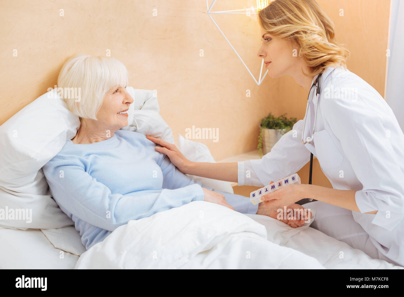 Tipo medico responsabile a convincere il suo anziano al paziente di rimanere a letto Foto Stock