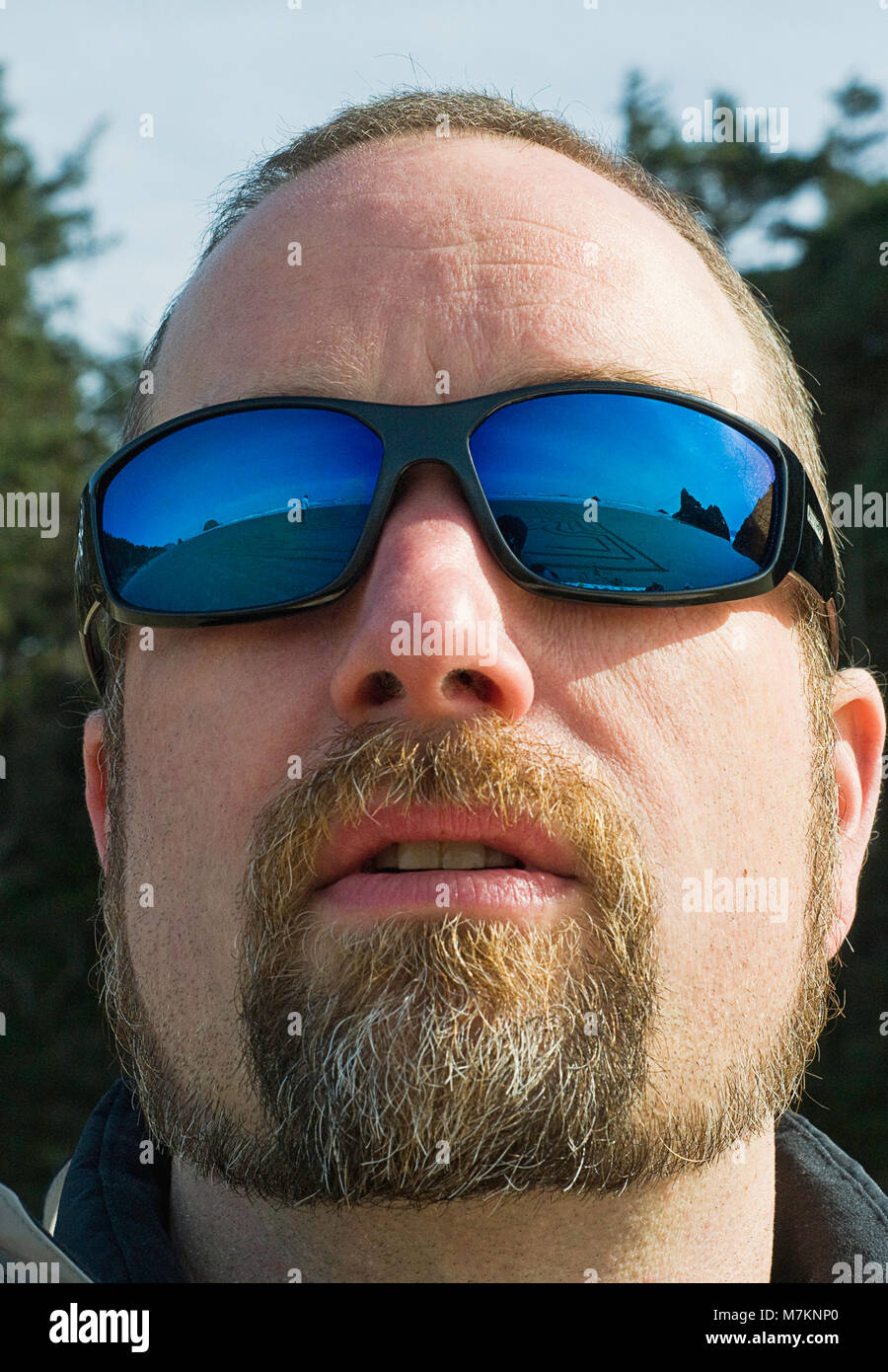 Un uomo che indossa gli occhiali da sole riflettendo Cannon Beach presso la Oregon Coast. Foto Stock