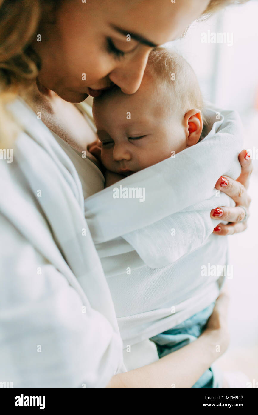 Piuttosto la mamma mentre tiene il suo nuovo nato figlio e dandogli un bacio sulla fronte Foto Stock