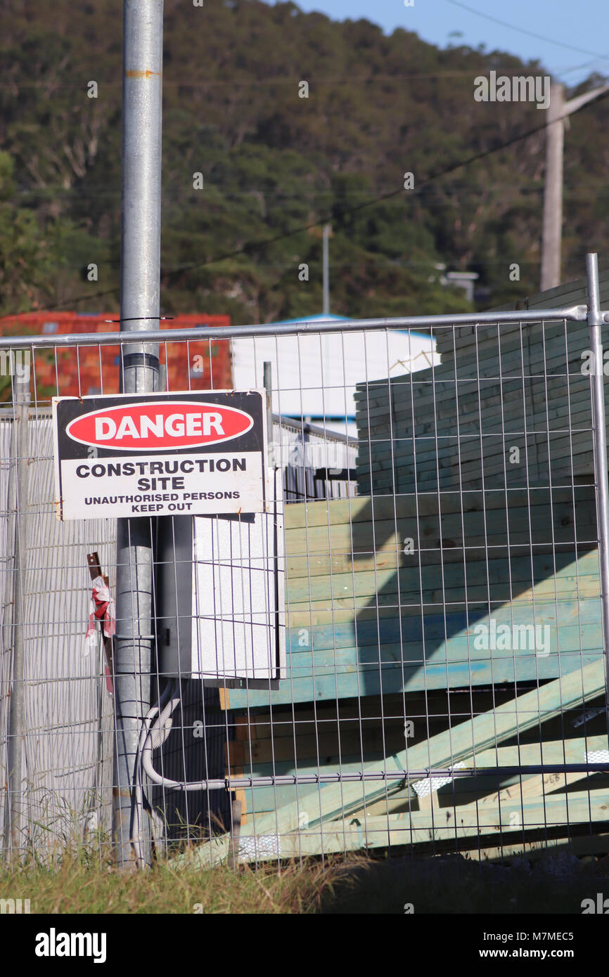 Recinzione temporanea intorno al sito in costruzione con segnaletica di pericolo Foto Stock