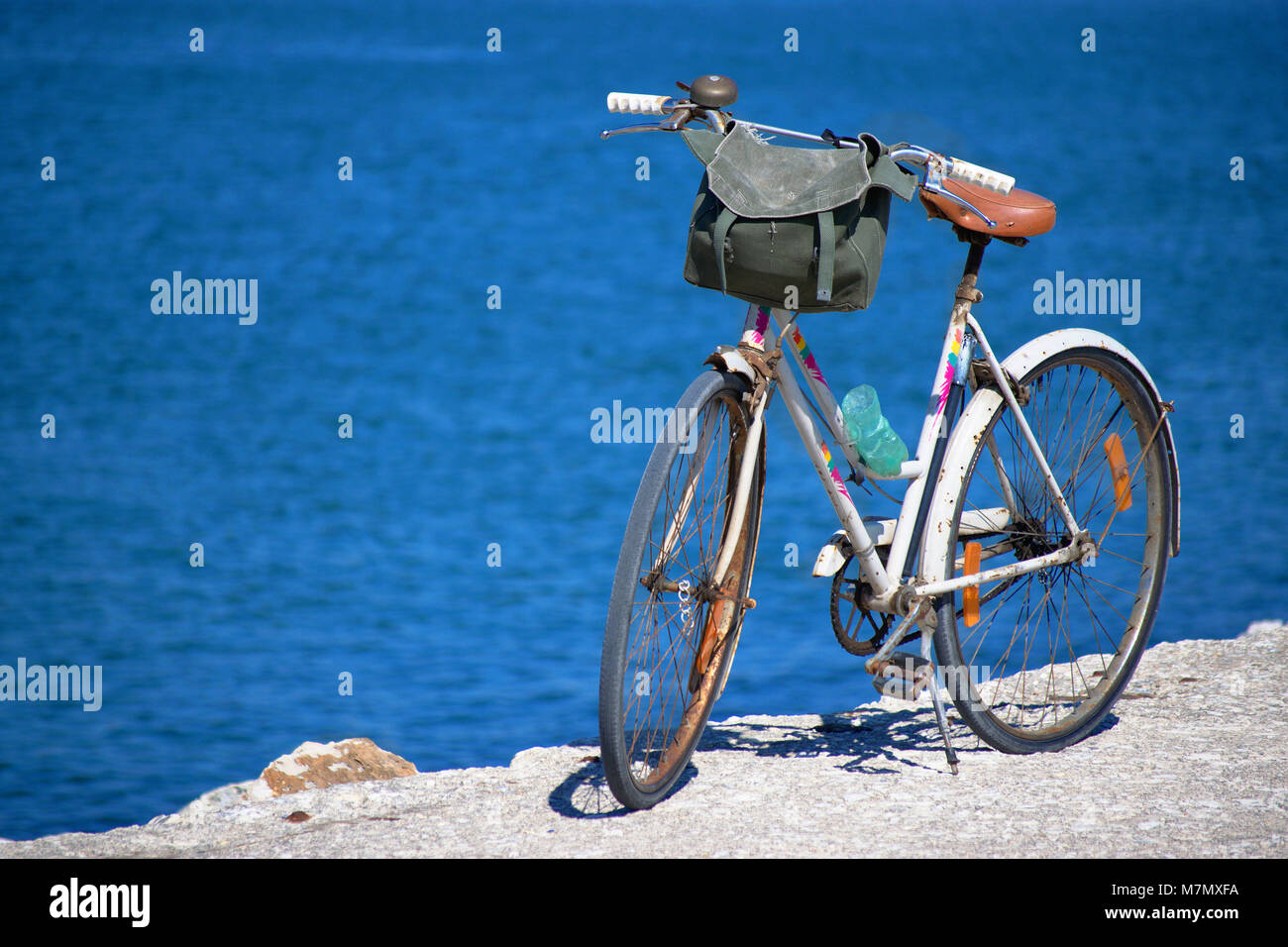 Vecchia bicicletta in piedi su un molo con il mare sullo sfondo, in una chiara giornata di sole. Foto Stock