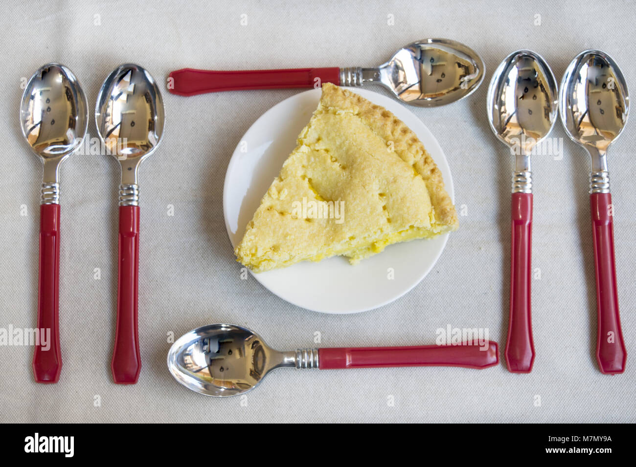 Cuneo di crostata di ricotta su alcuni piattini e tra colorate cucchiaio da dessert Foto Stock