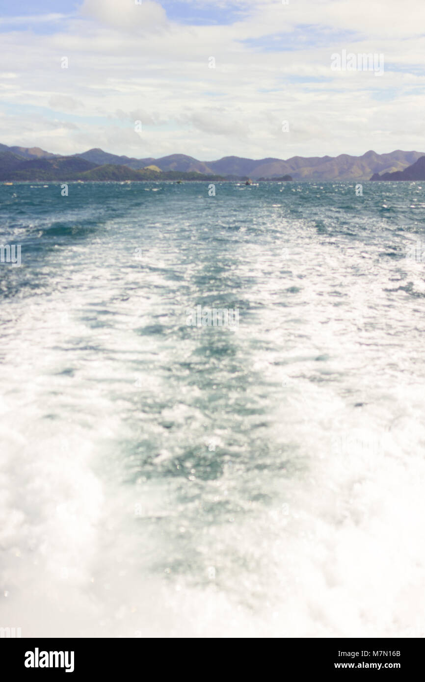 La vista dalla poppa di un traghetto passeggeri zangolatura fino un mare calmo guardando indietro su un tropicale del sud-est asiatico si isola che appena si allontanò dalla. Foto Stock