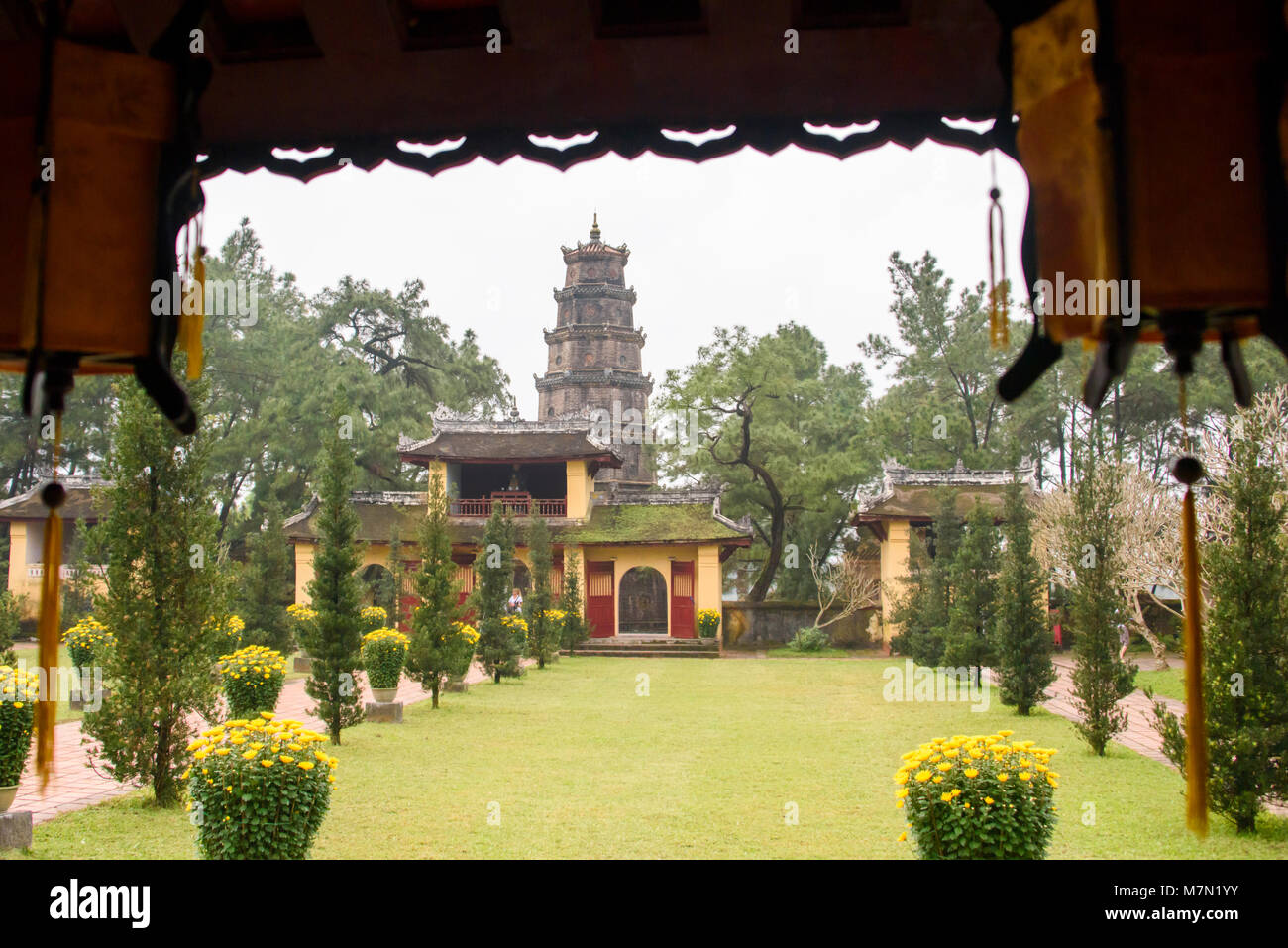 Giardino formale presso il rifugio buddista a Chùa Thiên Mụ (Pagoda della signora celeste, chiamato anche Linh Mụ Pagoda) , Hue, Vietnam. La sua iconica con sette piani pagoda è considerata come il simbolo non ufficiale della città.] Foto Stock