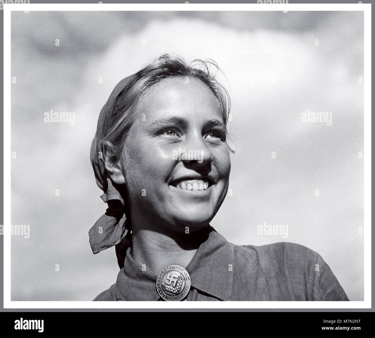 1930 WW2 Propaganda nazista immagine di stereotipi idealista ariano ragazza bionda che indossa una gioventù hitleriana Swastika emblema distintivo sorridente nel Terzo Reich futuro Foto Stock