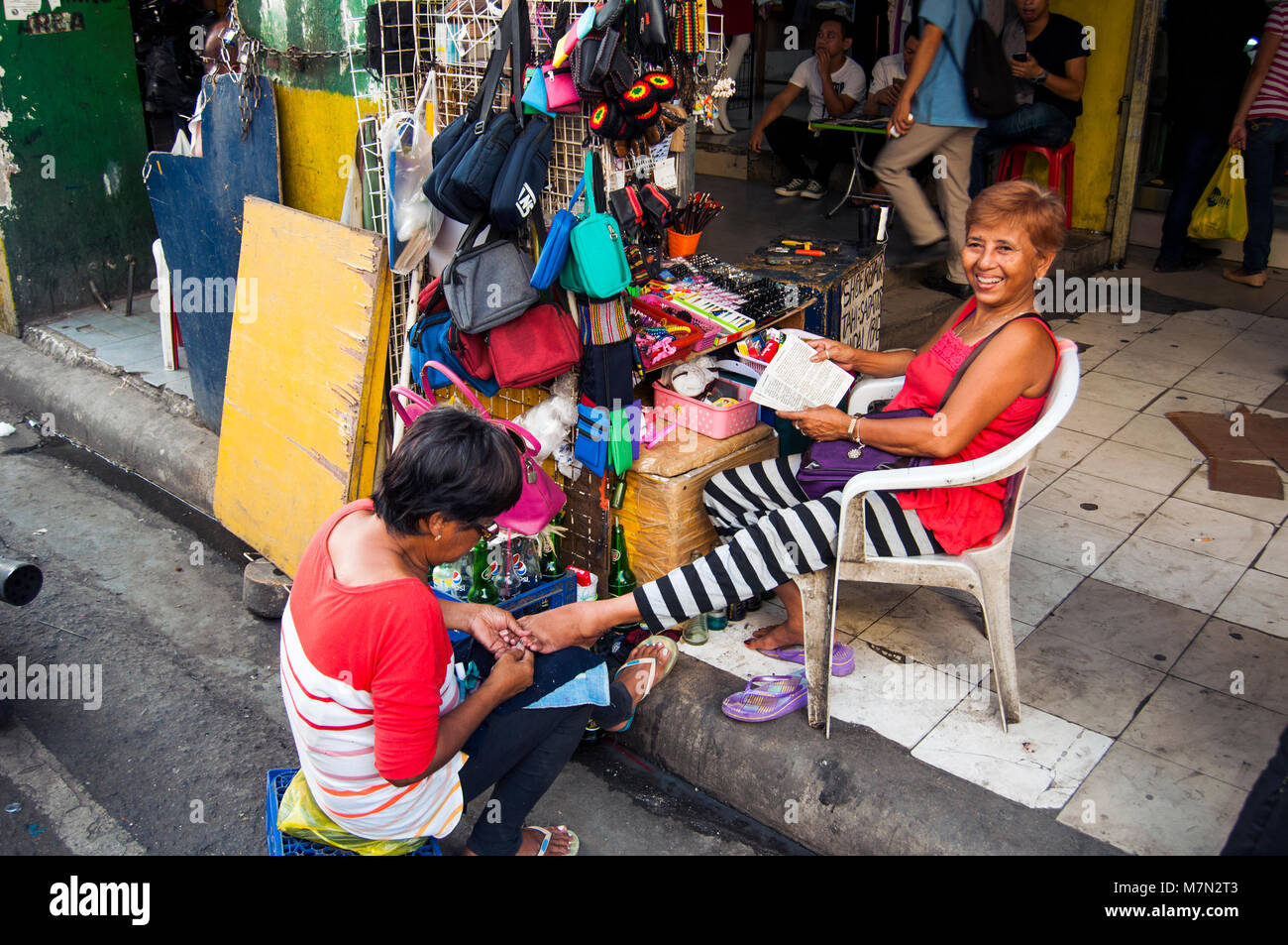 Donna pedicure di ricezione ad una bancarella di strada sul Colon Street, Cebu City, Filippine Foto Stock