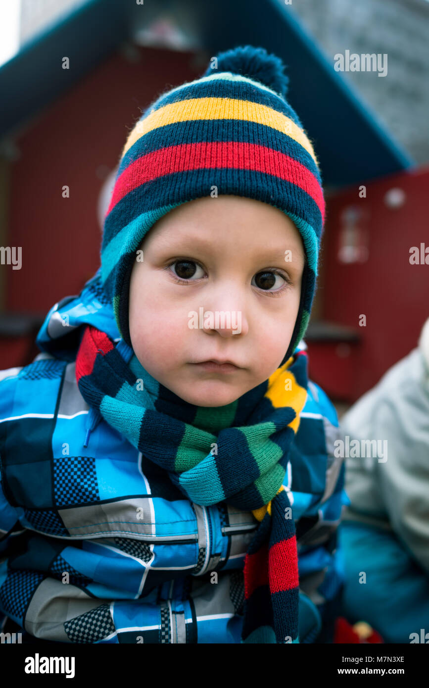 Ritratto di un po' di tristezza ragazzo accanto all'area giochi. Grave kid cercando nella fotocamera in cantiere Foto Stock