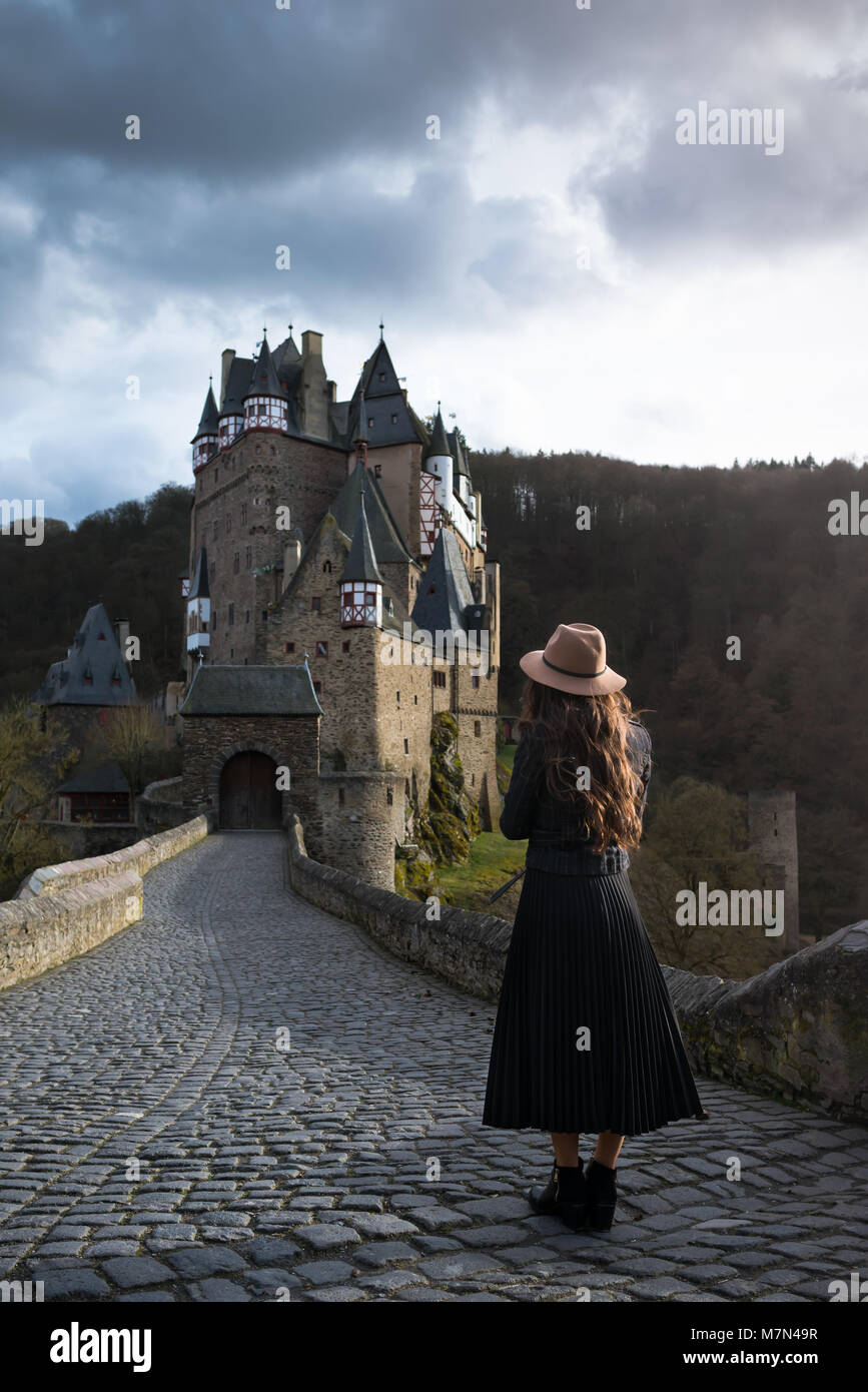 Giovane donna irriconoscibili sorge torna sulla strada che conduce ad un bel castello. Favoloso luogo medievale. Ragazza alla moda si trova a viaggiare in Europa Foto Stock