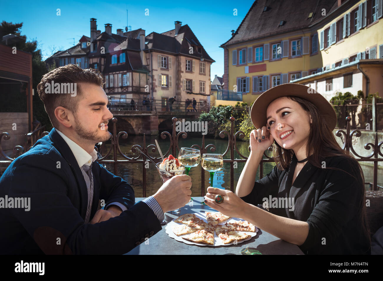 Due persone si siede insieme nella caffetteria locale con cibo e vino. Giovane donna con il mio ragazzo il pranzo in Alsazia. Moda giovane trattiene bicchieri di vino sulla terrazza Foto Stock